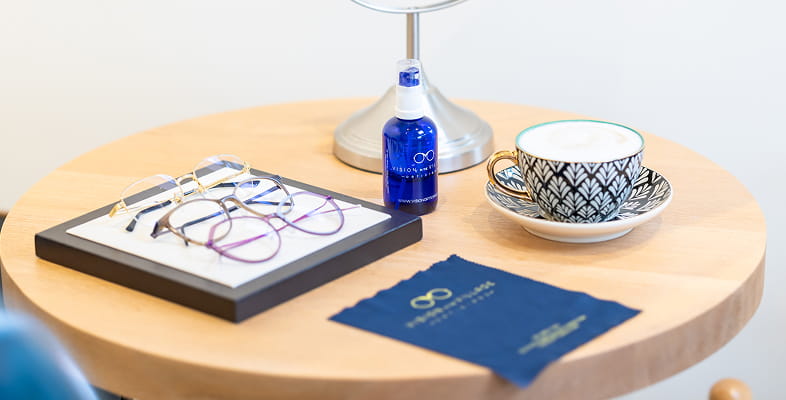 Lens, glasses and tea cup on table